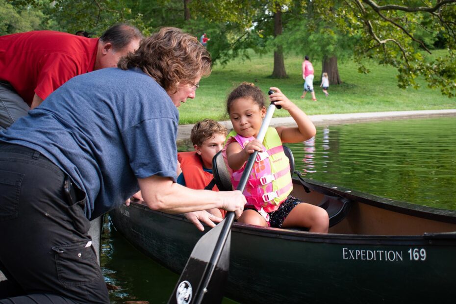 A woman teaching a kid how to row a boat