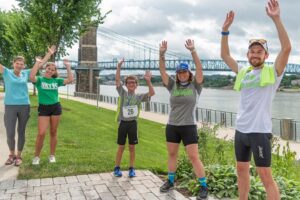 A family and racer throwing their hands in the air with excitement at the be.well race at Smale Riverfront Park.