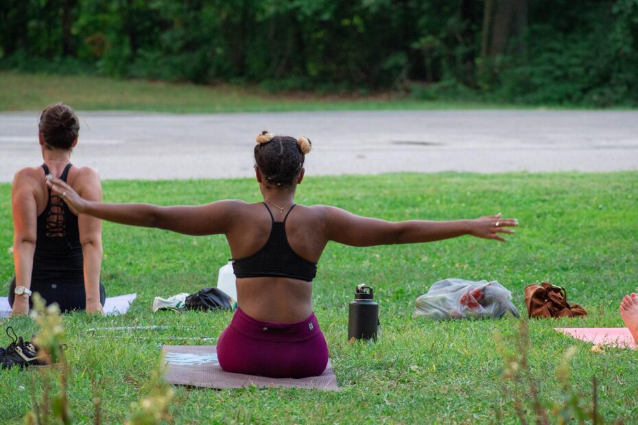 A woman with her arms outstretched, doing yoga in the park.