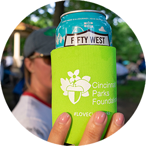 Woman holding up a beer can with an Cincinnati Parks Foundation logo on it