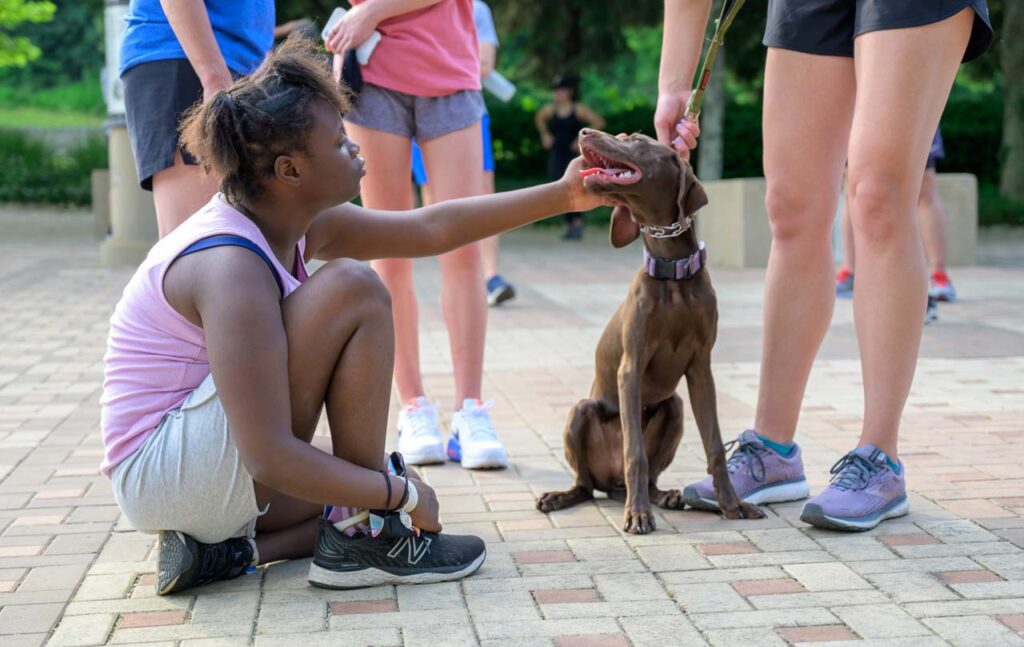 A be.well athlete petting her run buddy's dog.
