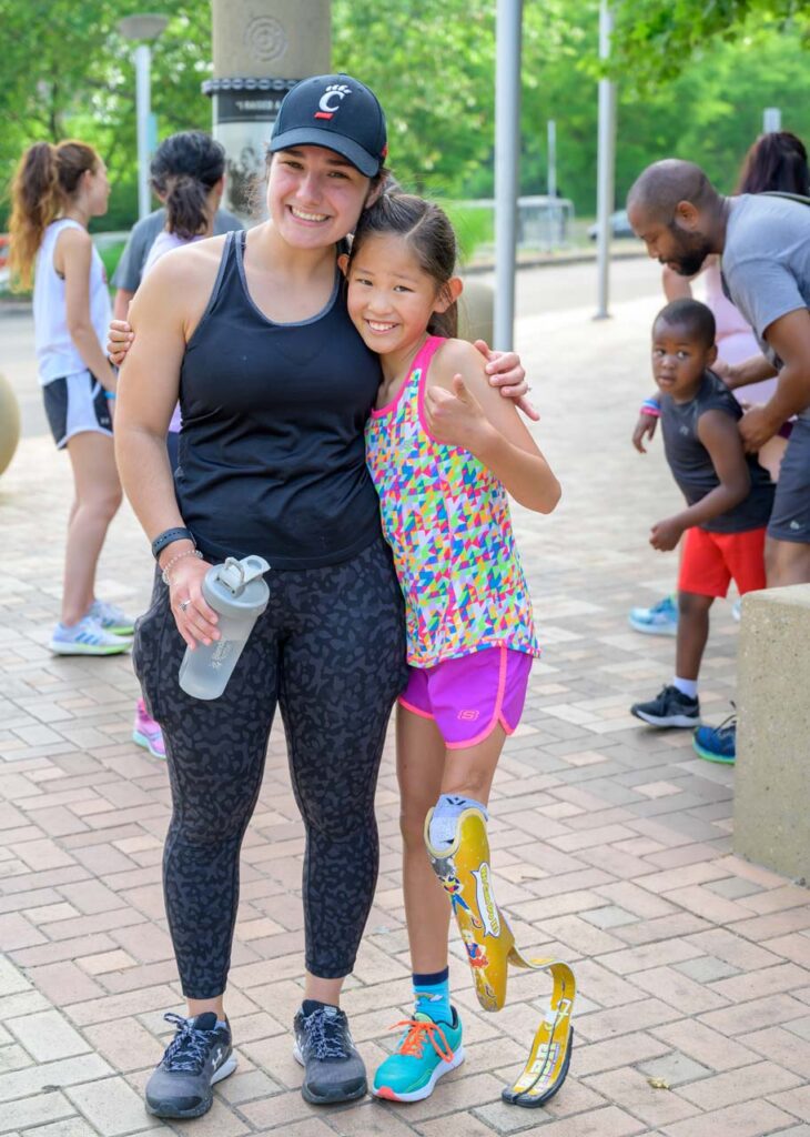 An adaptive athlete with her be.well Cincinnati Children's Hospital run buddy