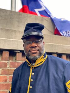 Man in uniform standing with the Juneteenth Flag in Eden Park