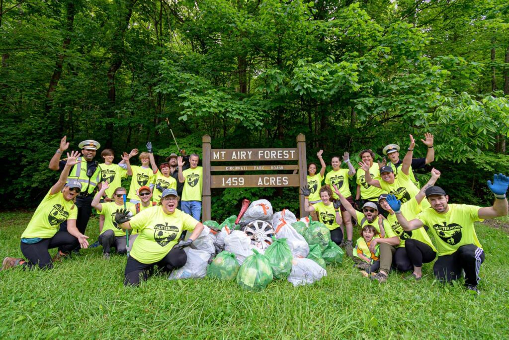 Large group of people posing with obLITTERator shirts and bags of trash