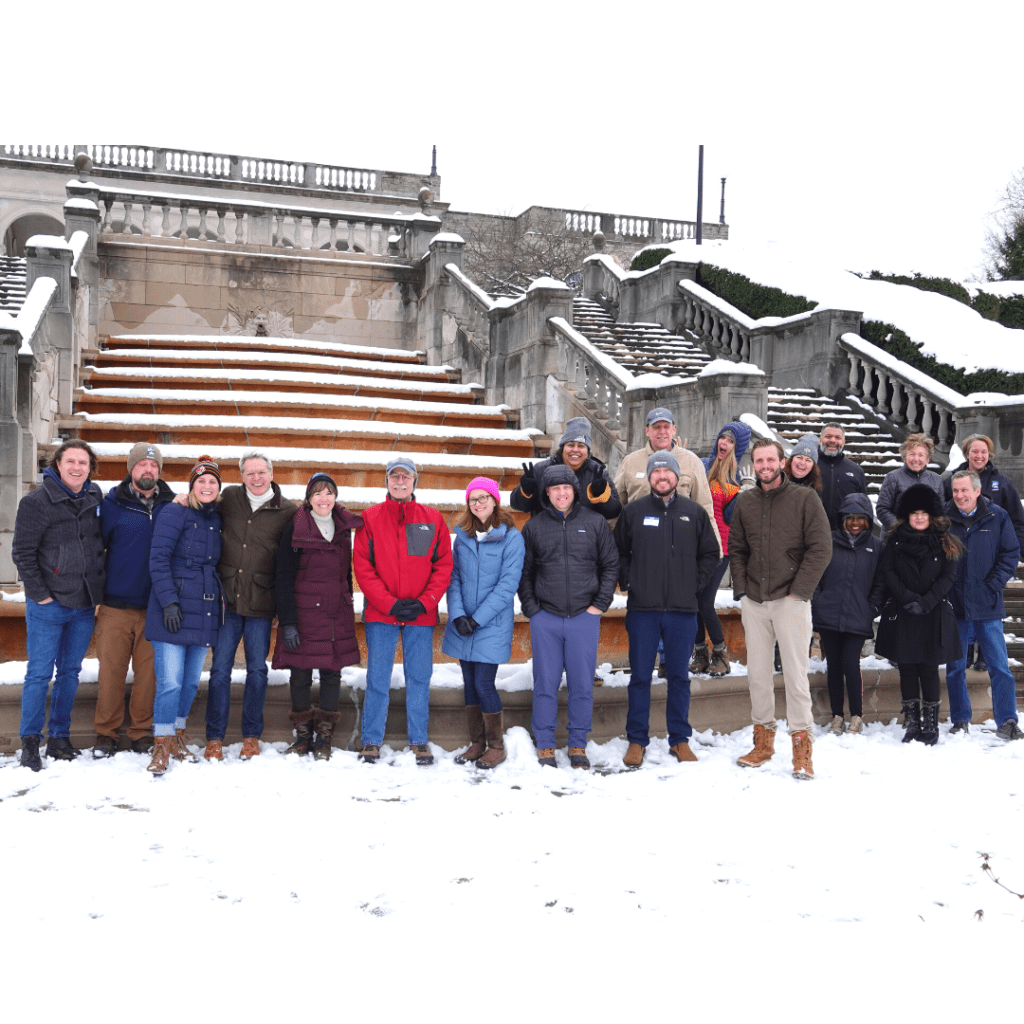 A group of people standing in front limestone steps.