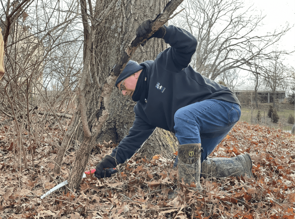 Man kneeling to pick up trash in the woods