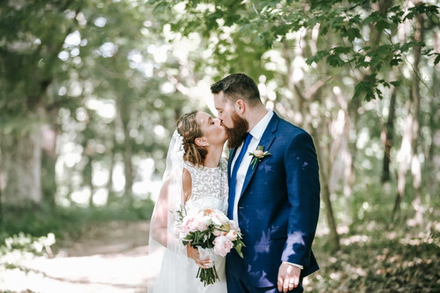 A bride and groom kissing on a wooded path