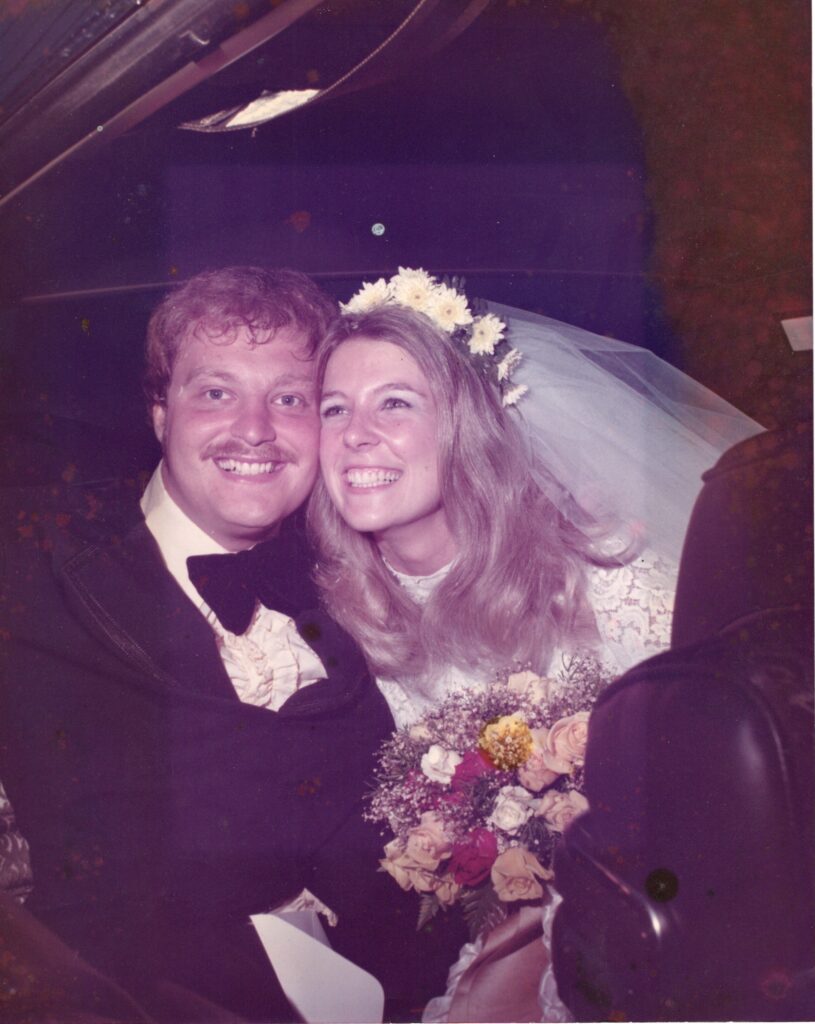 A bride and groom smiling at the camera.