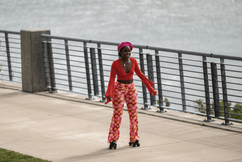 Woman in bright clothing on roller skates on a sidewalk in front of the river