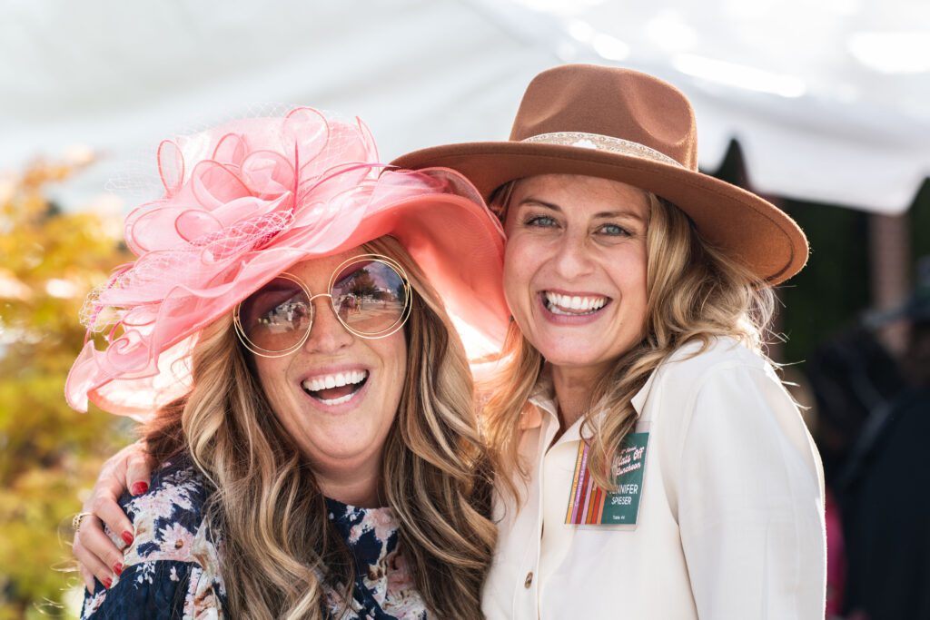 Two women smiling and wearing hats