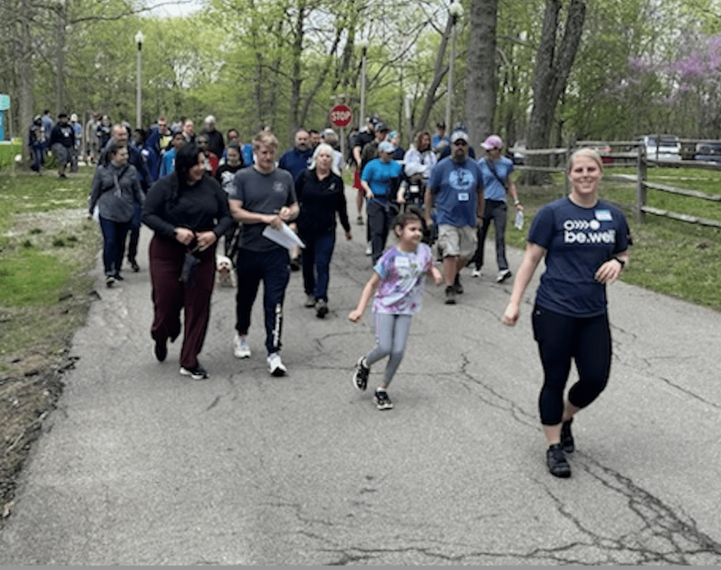 People walking down a wide path with trees and grass around them
