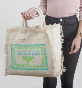 Tote bag with green and blue decorations hanging on woman's arm