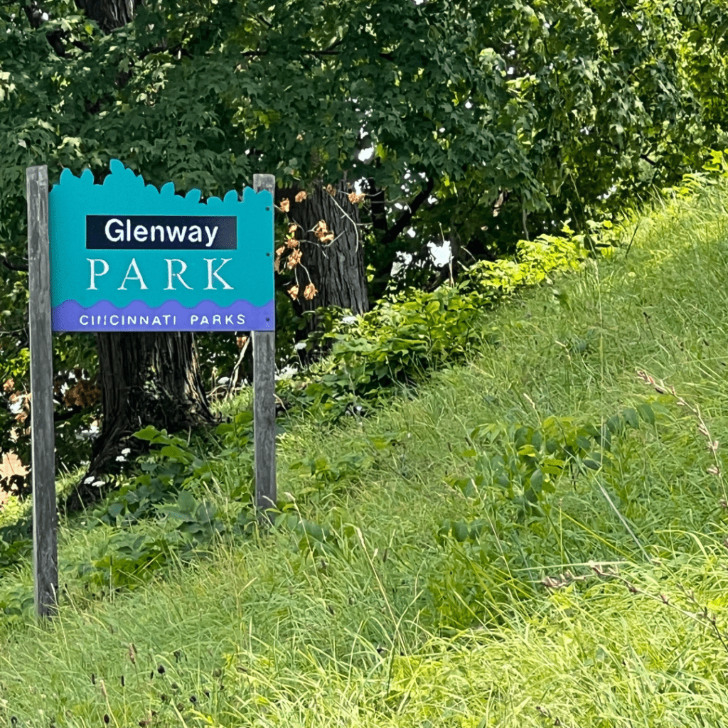 A picture of a park sign on a grassy hill