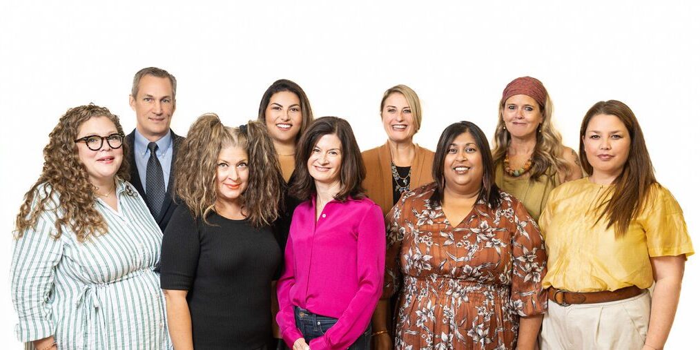 A group of people standing together. They are looking at the camera and smiling.