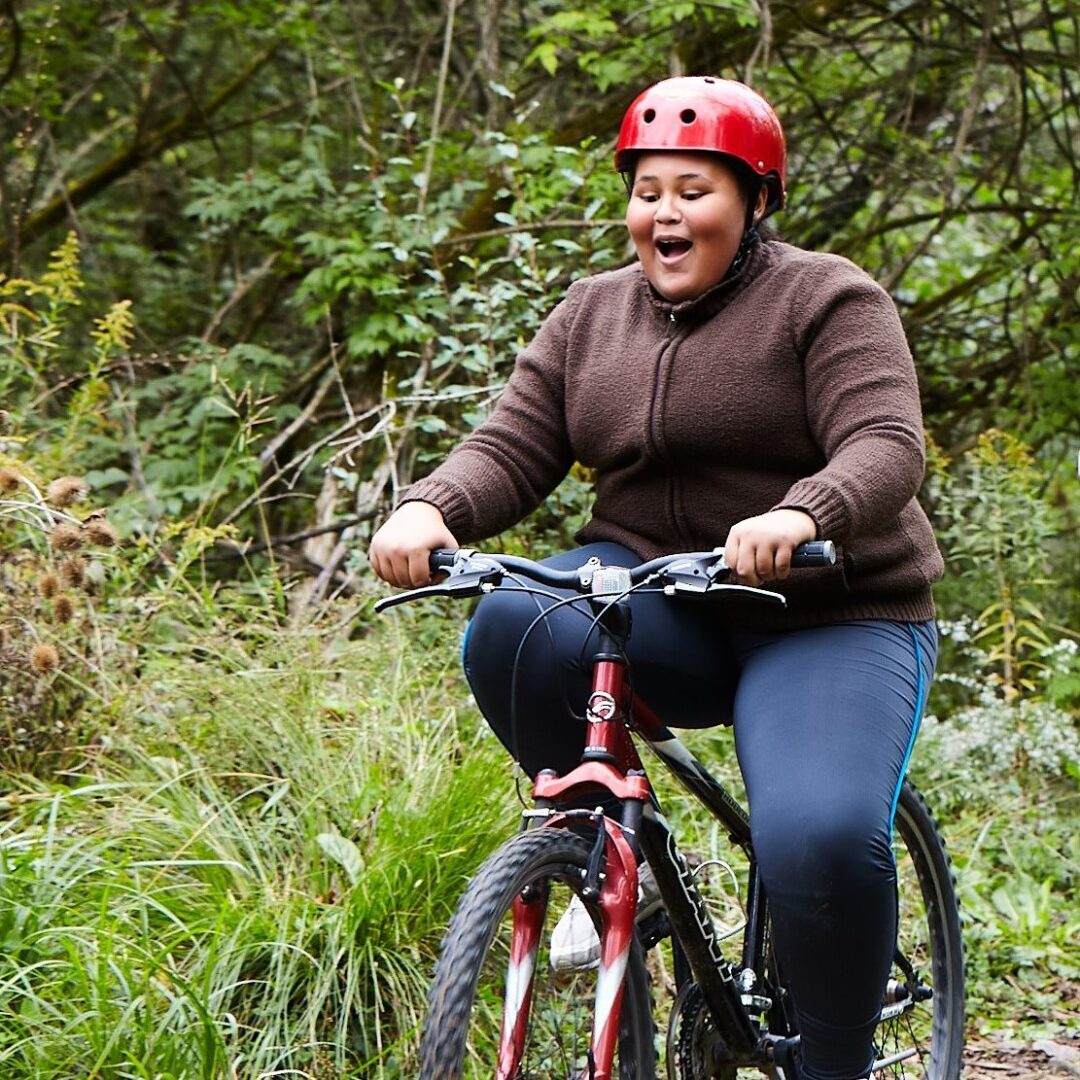 Person riding a bike on a mountain biking trail and smiling.